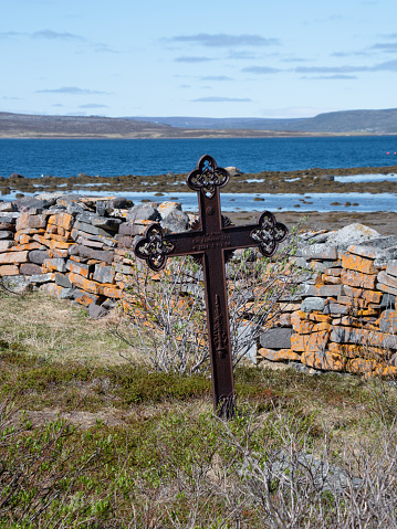 An old grave marker by a stacked stone wall at Nesseby Church in Northern Norway.