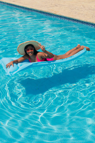 istock woman in bikini, wearing straw hat relaxing on inflatable in pool 1325501721