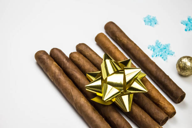istock Cigars as a gift on white background. Cigars with gold bow. 1325504880