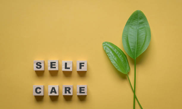 istock Self care word with green leaf on yellow background. 1325505680