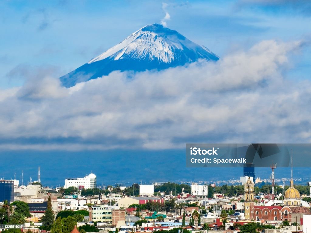 Volcano and City Popocatépetl (“smoking mountain”), an active volcano and he second highest peak in Mexico dwarfs the city of Puebla. Mexico Stock Photo