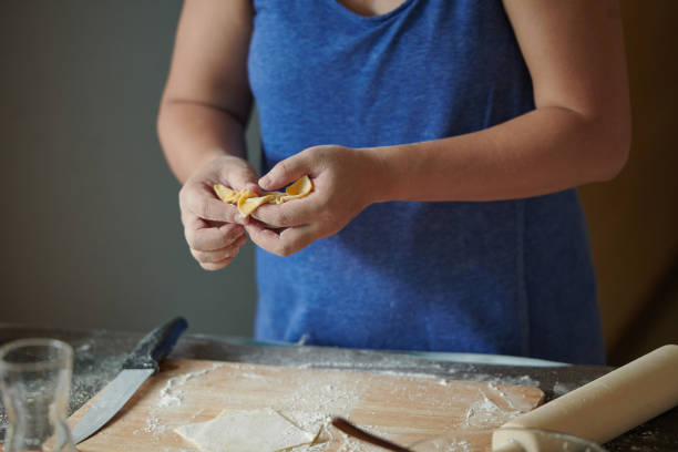 istock Front view of woman's hands making meat dumpling with wooden rolling pin. The process of making homemade dumplings. Minced meat on dough, the process of cooking Italian ravioli. Russian food. 1325511596