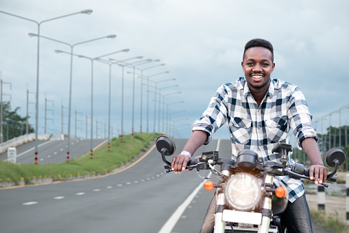 African biker man riding a motorcycle rides on highway road