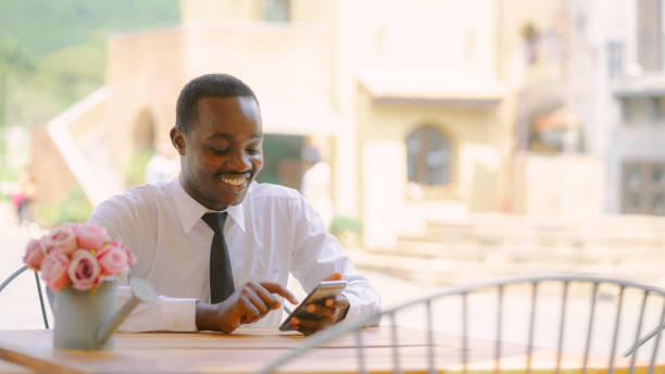 Handsome smiling african business man using smartphone in cafe restaurant.16:9 style stock photo