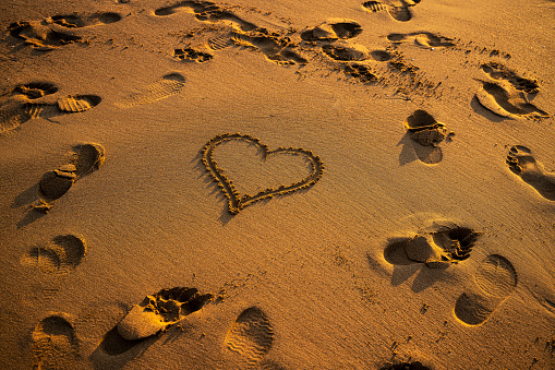 Drawing heart shape with footprints on the beach