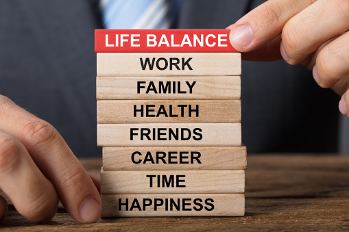 Closeup of businessman building life balance concept with wooden blocks on wood