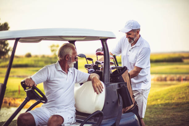 코트에서 두 명의 시니어 남자 골퍼. 골프 카트에 앉아 남자. - senior couple golf retirement action 뉴스 사진 이미지
