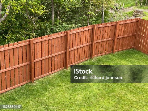 istock Wooden garden fence coated with medium oak colour paint 1325530417