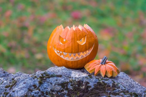 istock Scary smiling halloween pumpkin with nasty face on a stone 1325531105