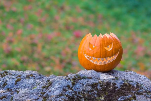 istock Scary smiling halloween pumpkin with nasty face on a stone 1325531136