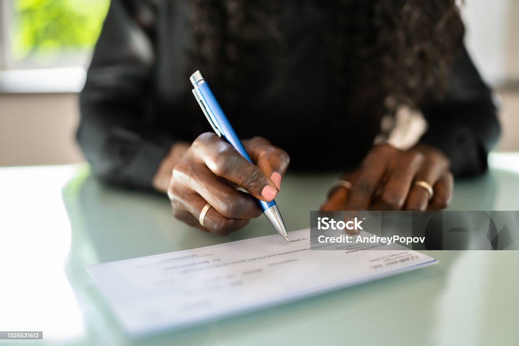 African Woman Writing Check African Woman Writing Check. Payroll Salary Cheque Check - Financial Item Stock Photo