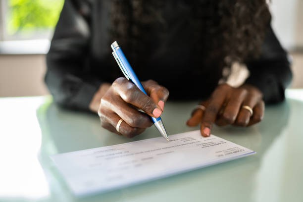african woman writing check - 支票 圖片 個照片及圖片檔