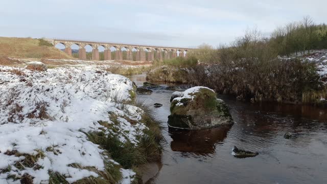 River Fleet flowing through a snow covered landscape and railway viaduct