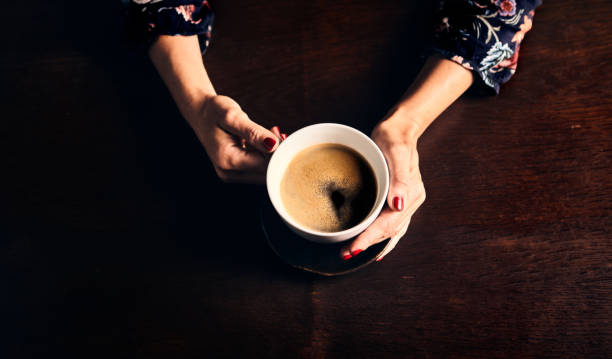istock Womans hands holding a cup of coffee. From top 1325534899