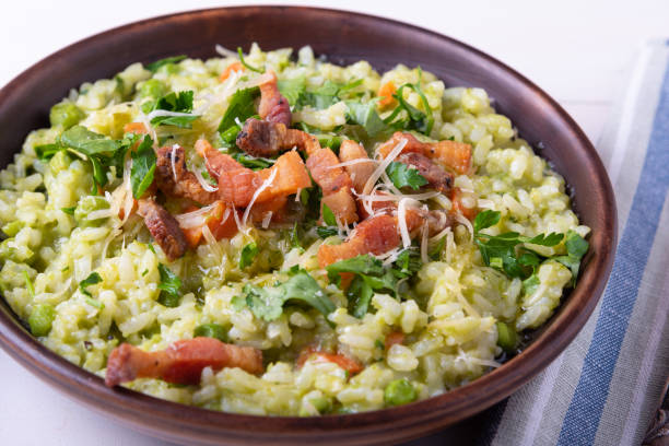 homemade risotto with peas and fried crispy bacon, pancetta and grated cheese on a plate, close-up - pancetta imagens e fotografias de stock