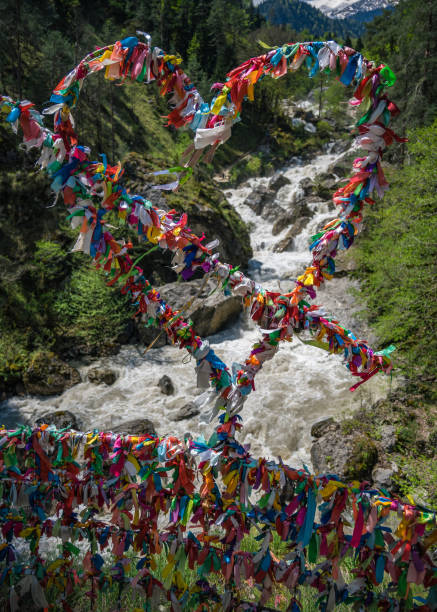 el aspecto romántico de cintas de colores en forma de un corazón y una flecha. el río áspero de las rocas poderosas de la cresta de ghagra en abjasia fluye en el fondo. viajes, senderismo y turismo. - flowing travel locations ribbon form fotografías e imágenes de stock