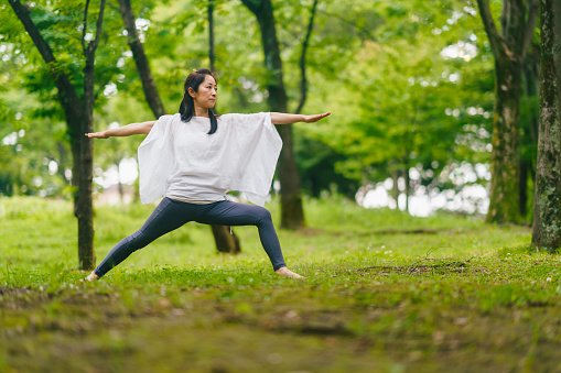 A woman is practicing breathing exercise and meditation and yoga in nature.