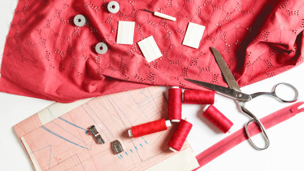 istock Tailoring concept. beautiful red fabric with sewing thread, scissors, chalk and spool on a white background. Top view. Flat lay 1325544194