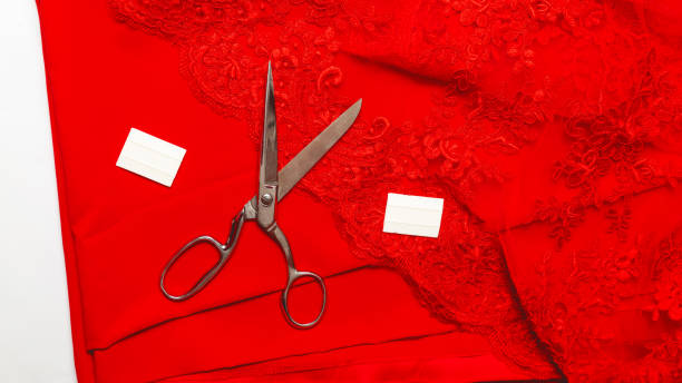 istock Tailoring accessories. Scissors and red satin and guipure fabric on table, top view. sewing business 1325544969