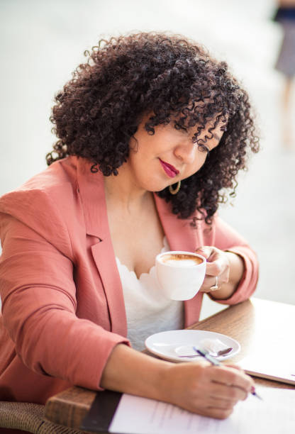 istock Business woman sitting in cafe writing on document. 1325548459