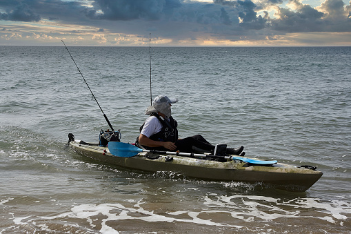 Man fishing in a kayak in the sea. Fisherman kayaking in the Mediterranean sea