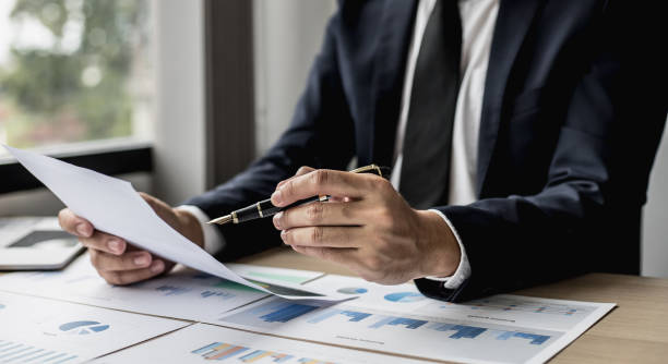 istock A businessman using a pen to point a pie chart on a document, he is reviewing financial documents from the finance department that summarizes monthly data for him to review before attending a meeting. 1325550060