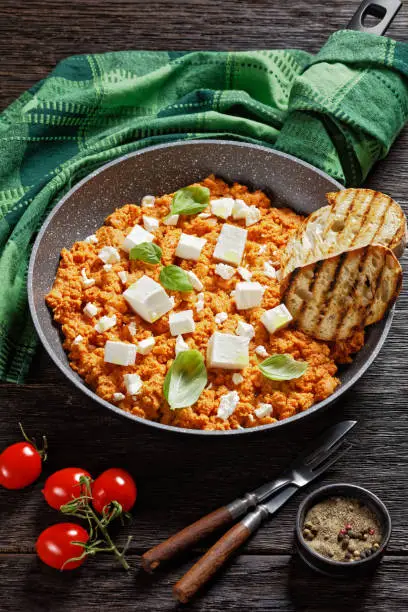 Strapatsada, eggs scrambled with tomatoes and feta cheese in a skillet with toasted bread, horizontal view, greek cuisine, close-up