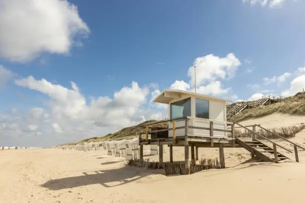 Beautiful beach on the German island of Sylt with white sand and a sunset sky. a lifeguard station and empty  beach chairs.
