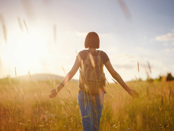 istock young woman with a backpack in a field at sunset 1325554592