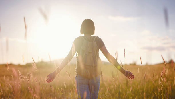 istock young woman with a backpack in a field at sunset 1325554649