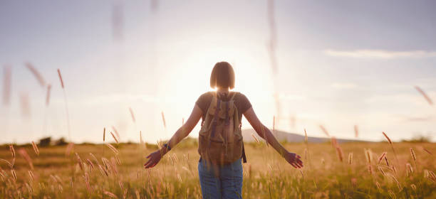 istock young woman with a backpack in a field at sunset 1325554775