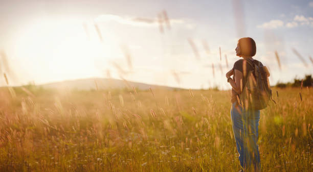 istock young woman with a backpack in a field at sunset 1325554872
