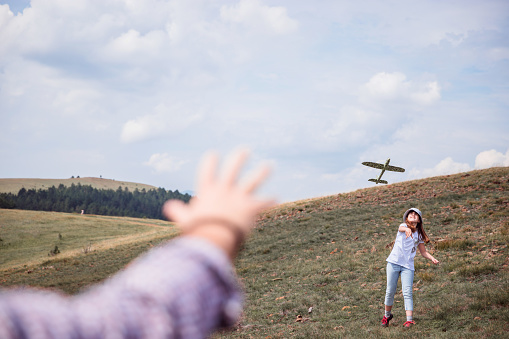 Girl playing with her dad with a model plane