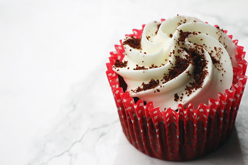 A red velvet cupcake with white frosting.