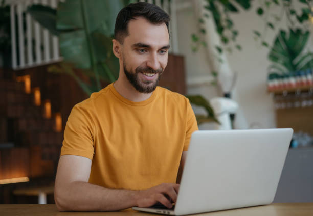 自宅で仕事、ラップトップコンピュータを使用して笑顔の男。職場に座っている若いフリーランサーのコピーライタータイピングの肖像画。学生の勉強,遠隔学習,検索,オンライン教育 - marketing internet customer searching ストックフォトと画像