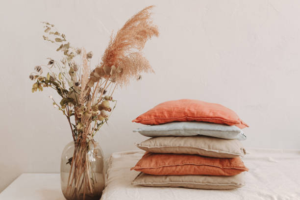 istock A glass vase with dried flowers standing next to a stack of pillows with different colors and natural materials 1325565657