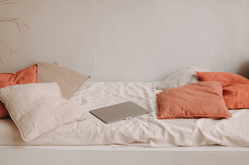 MacBook acostado en una cama hecha de materiales naturales con almohadas acogedoras photo