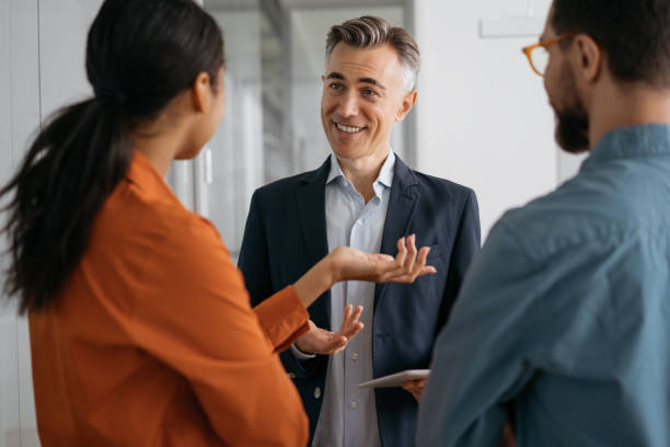 istock Colleagues meeting, planning start up, talking, cooperation, working in office. Mature confident mentor or business coach teaches people at business seminar, explaining information, sharing ideas 1325565977