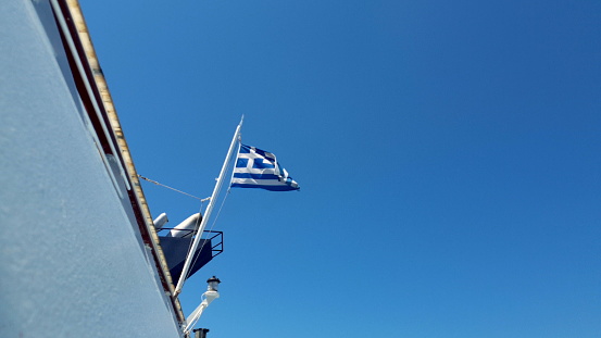 Greek flag waving in the back of a ship in the ocean