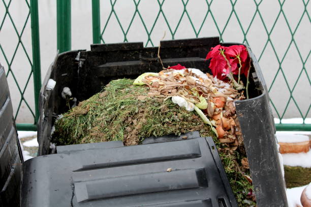 istock Top of broken old destroyed full black plastic compost bin next to metal fence covered with freshly fallen snow 1325570180