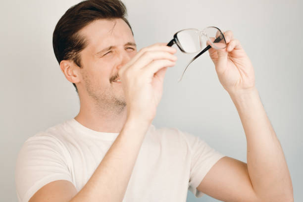 istock Vision problems concept, eye disease. Young man holding glasses and squinting, indoors close-up 1325571438