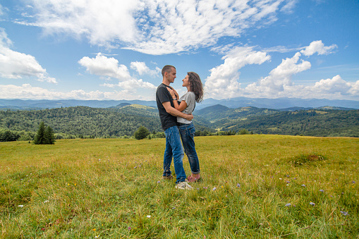 Young couple hugs on amazing mountain landscape background.
