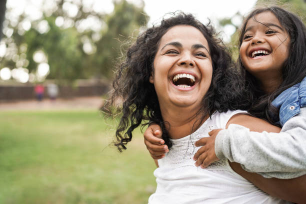 glückliche indische mutter spaßt mit ihrer tochter im freien - familie und liebe konzept - fokus auf mama gesicht - lächeln stock-fotos und bilder