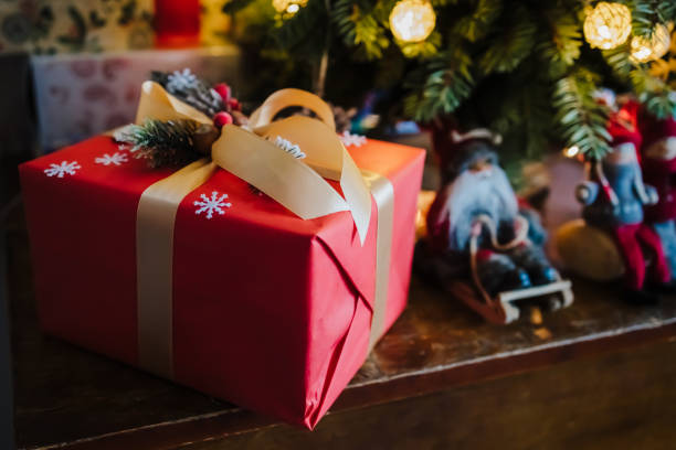 istock beautifully wrapped red gift box under the christmas tree, top view 1325579758