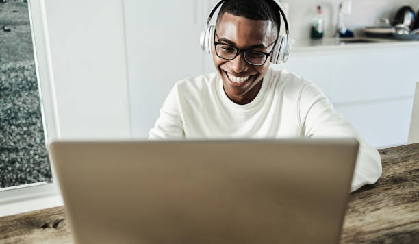 istock Young african man using laptop computer while wearing headphones at home - Focus on face 1325579777