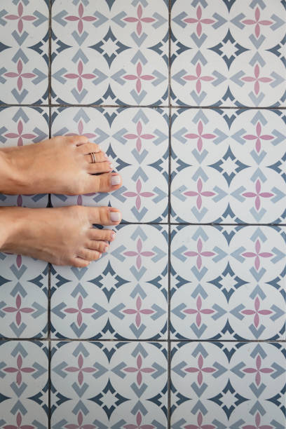 istock Young female bare feet with a ring on a toe on a light tile with a Turkish - Moroccan pattern. View from above. Copy space 1325580983