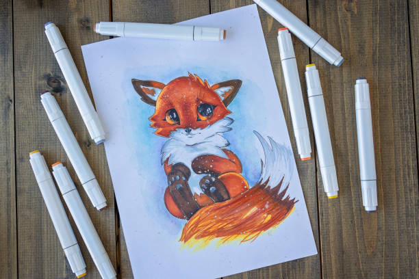 Flat lay with sketching ittle red-haired cute fox with a bushy tail. All placed on wooden table picture and markers. Hobby. Drawing fox. Top view. Soft focus