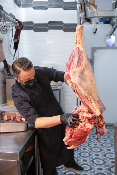 istock Butcher cuts up fresh farm meat carcass in his store 1325587271