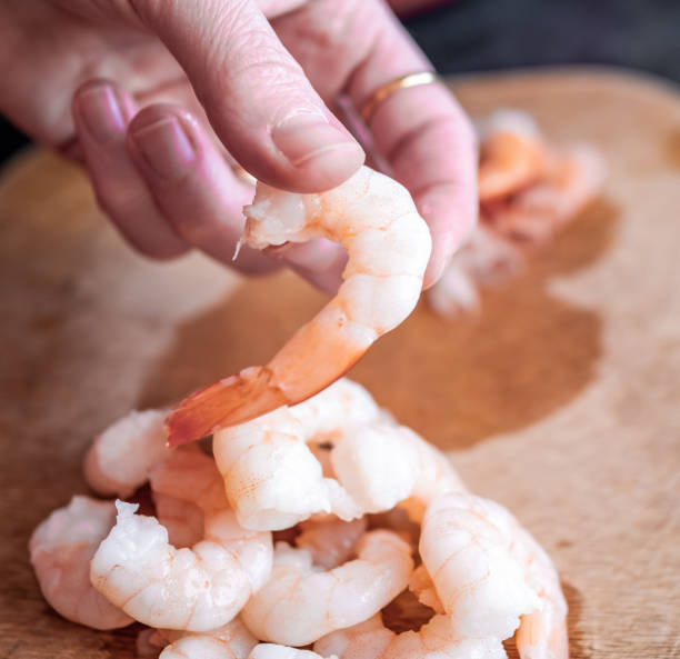 istock Unidentified chef removing the tails from king prawns 1325591100