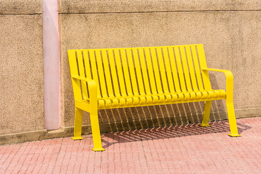 Colored yellow bench in a park outdoor garden